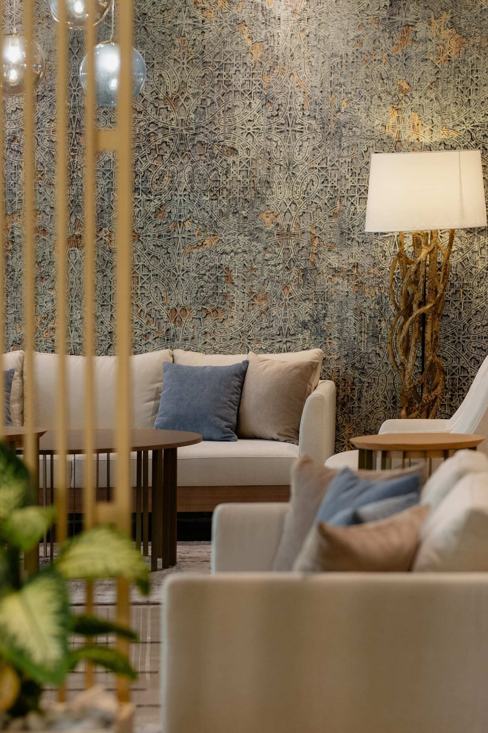 Un salon moderne avec un papier peint à motifs, un canapé, une table basse et une lampe.