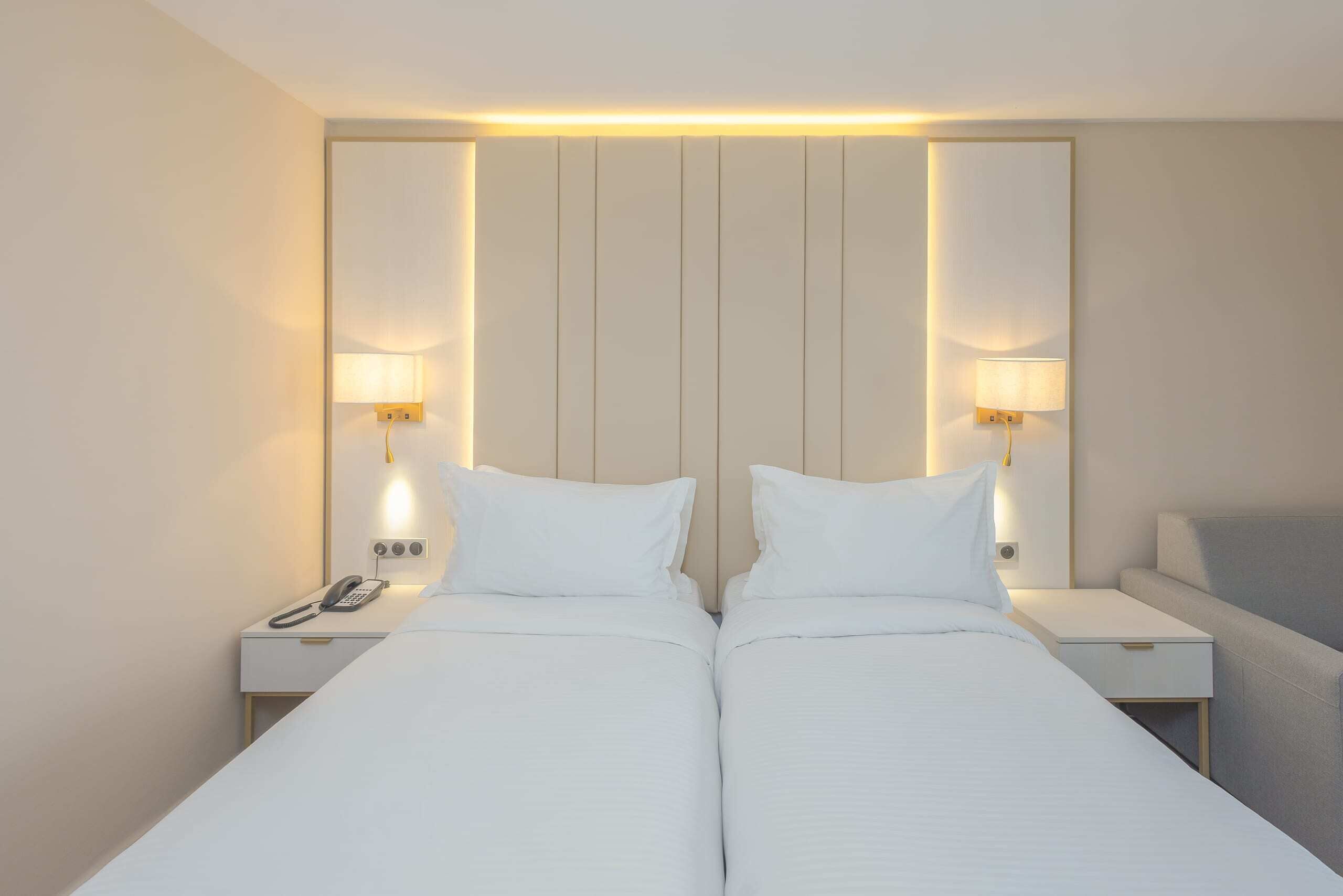 Een tweepersoonsbed met twee nachtkastjes, elk voorzien van een lamp en een telefoon.