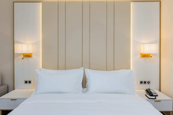 A hotel room with a large bed, two bedside tables, a lamp on each table, and a phone on one of the tables.