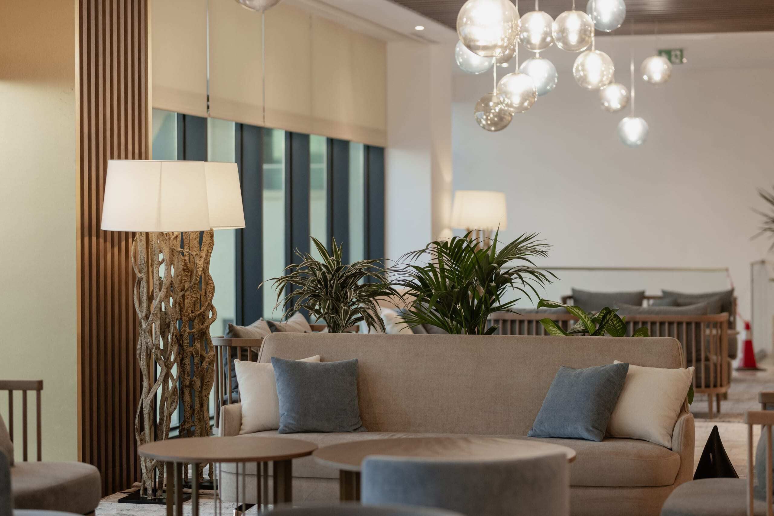 Un espace détente moderne avec un canapé, des tables rondes et des lampes sphériques suspendues.