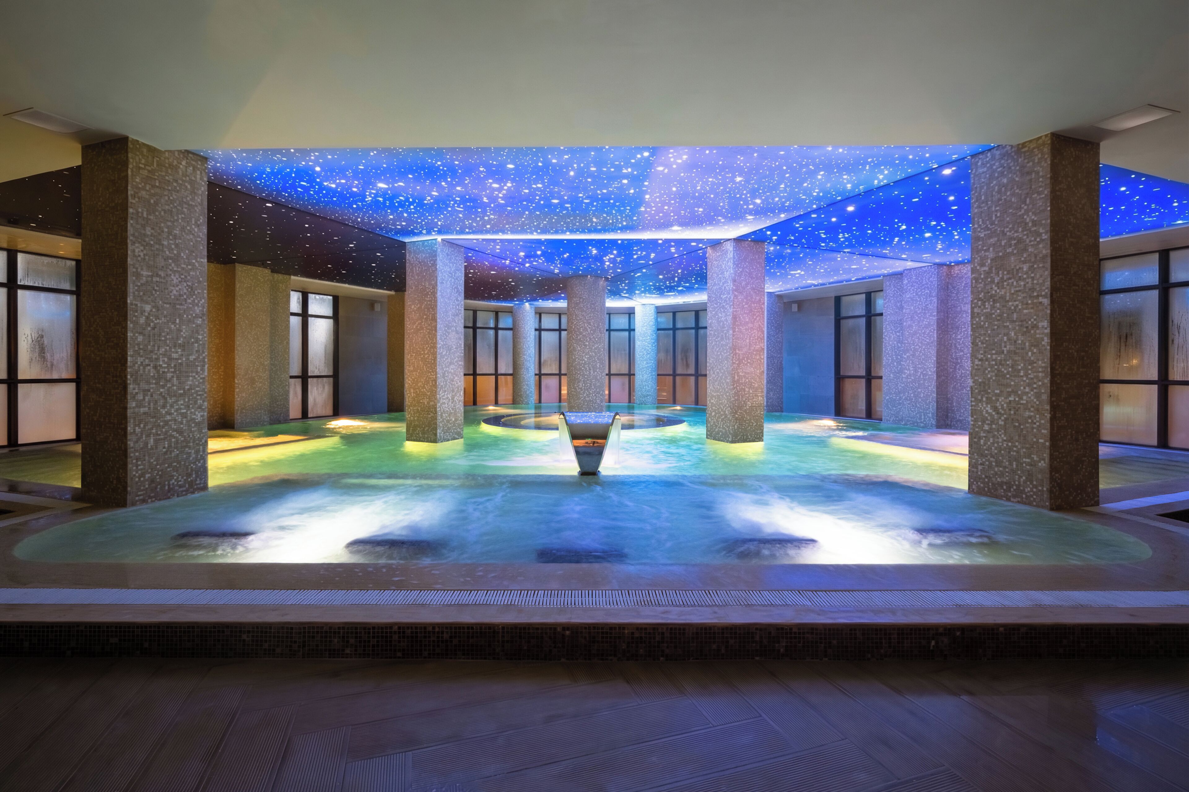 Un espace de bien-être doté d’un plafond étoilé, d’une fontaine centrale et de grandes colonnes.