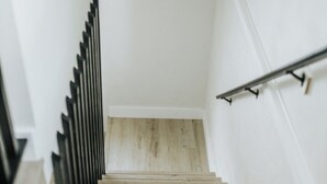 Eine Holztreppe mit Metallgeländer, weißen Wänden und Holzboden.