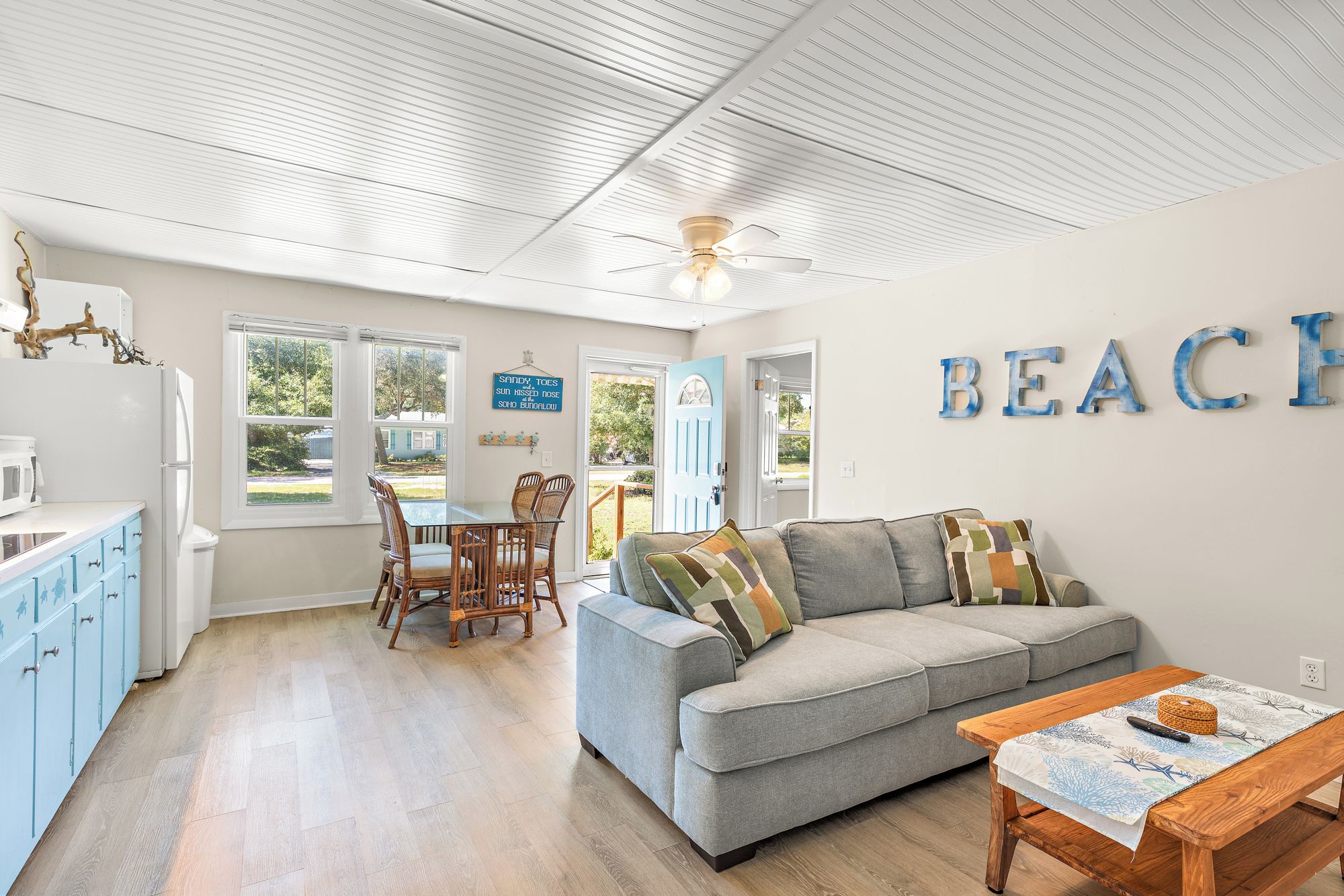 Un intérieur moderne comprenant un coin repas, un canapé et un mur sur lequel est inscrit le mot « PLAGE ».
