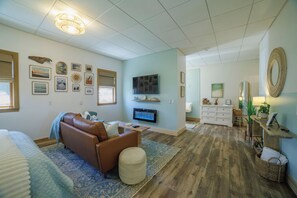Ein Wohnzimmer mit einem braunen Sofa, einem Fernseher und einer Wand mit gerahmten Bildern.
