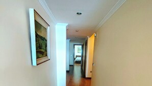 Un pasillo con suelo de madera, un cuadro en la pared izquierda y una puerta a la derecha.