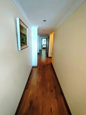 A hallway with wooden flooring, a framed picture on the left wall, and a door on the right. - Vistamar Altea Beach (Altea)