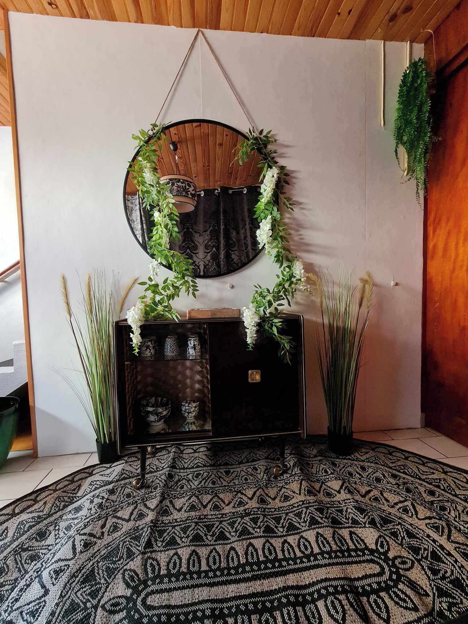 A room with a round mirror, a dark wooden cabinet, and a patterned rug.