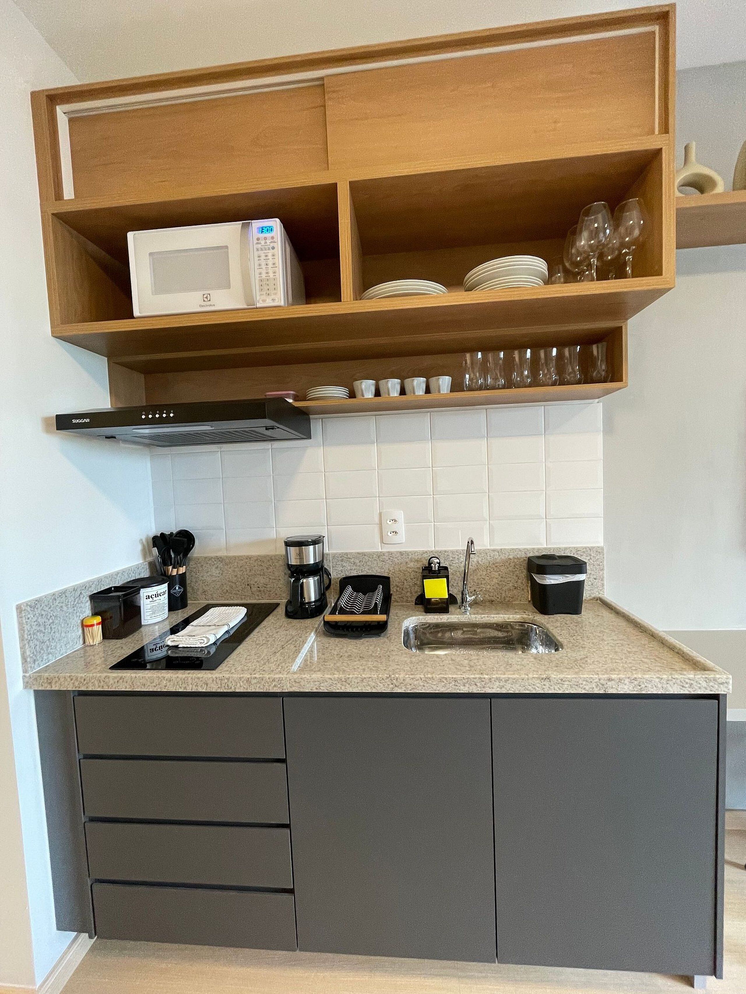 A kitchen with a microwave, coffee maker, and various utensils on the counter.