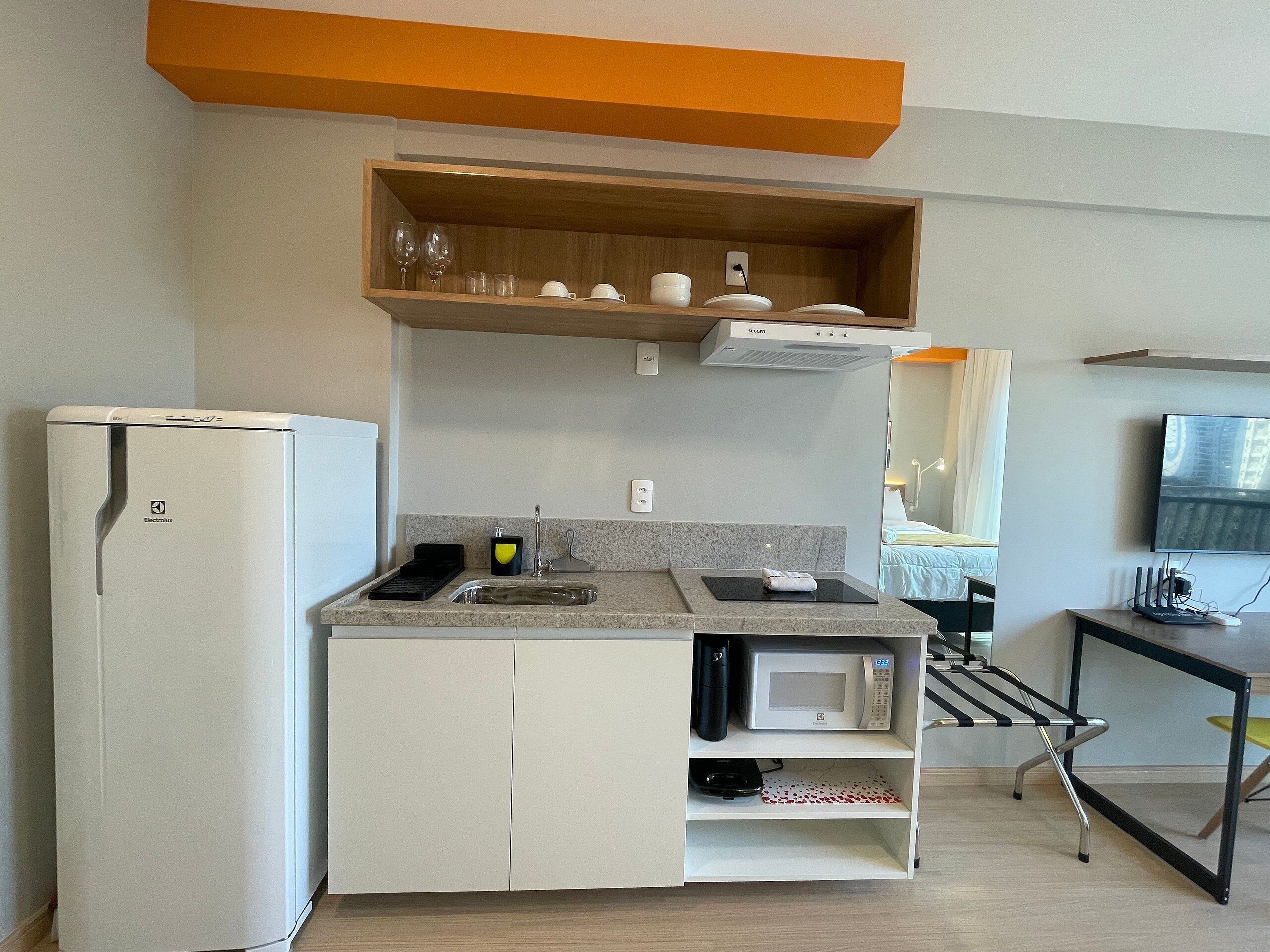 Eine kleine Küchenzeile mit Kühlschrank, Mikrowelle, Spüle und einem Hängeschrank.