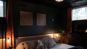 A bedroom with a bed, nightstand, lamp, wall art, and a TV. - Gateway to the Gorge (Portland)