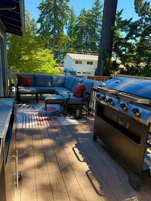 Eine Terrasse mit Grill, einer Eckcouch und einem Esstisch.
