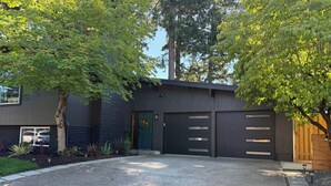 A modern two-story house with a driveway, garage, and surrounding greenery. - Gateway to the Gorge (Portland)