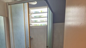 A bathroom with a glass-enclosed shower, a toilet, and a sink with a mirror. - House with 3 air-conditioned bedrooms. (Lamentin)