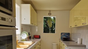 A kitchen with a microwave, oven, and refrigerator. There is a window with a view of trees. - House with 3 air-conditioned bedrooms. (Lamentin)