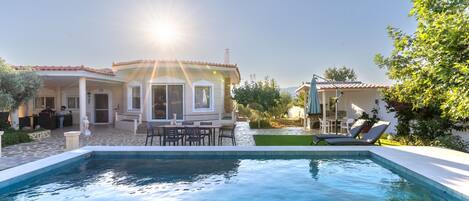 A pool area with a house, outdoor furniture, and a clear sky.