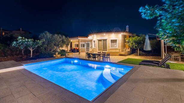 Una piscina amb una zona de terrassa, una zona de seients coberta i una casa al fons.