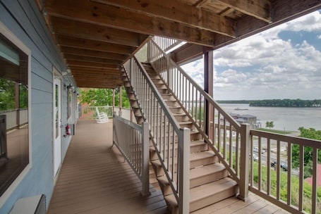 A wooden deck with a staircase leading to a covered area overlooking a river.