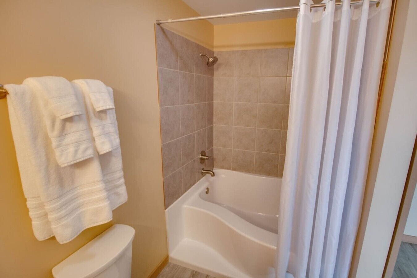 A bathroom with a bathtub, a toilet, and a shower curtain.