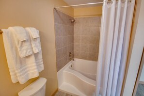 Une salle de bain avec une baignoire, des toilettes et un rideau de douche.