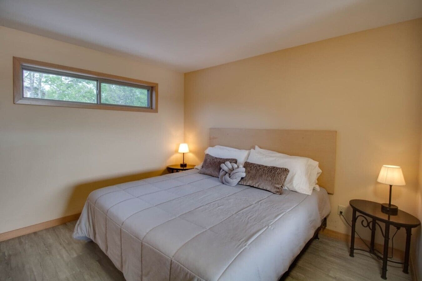 Een slaapkamer met een bed, twee bedlampen, een raam en een nachtkastje.