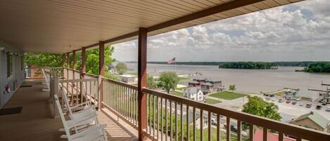 A covered balcony with a view of a river and distant buildings.