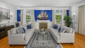A living room with two sofas, a fireplace, and a large ship model on the wall. - Luxury Lake Front w/ Grill and Fire Pit - Perfect for Autumn Retreat (Yarmouth)