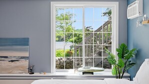 A bedroom with a large window, a bed, a painting, and a plant. - Luxury Lake Front w/ Grill and Fire Pit - Perfect for Autumn Retreat (Yarmouth)