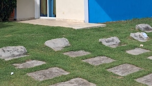 Un edificio moderno su due piani, con facciata blu, un balcone con ringhiere bianche e un piccolo ingresso.