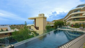 Une piscine entourée d’une rambarde en métal, bordée de verdure et surplombée d’immeubles dotés de balcons.