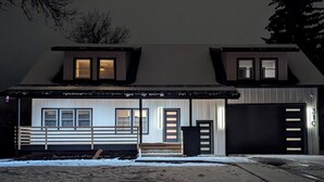 Une maison à deux étages avec un grand porche à l’avant, un garage et une allée recouverte de neige.