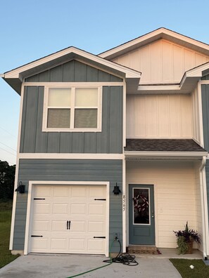 A two-story house with a garage, a front door, and a small porch area. - Navarre Beach Brand-new townhome! (Navarre)