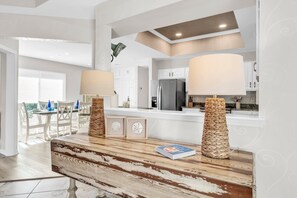 A modern kitchen with white cabinets, a stainless steel refrigerator, and a wooden island with two lamps. - 🌴Serenity Cottage | Walk to Beach | Golf Cart (LSV)🌴 (Miramar Beach)