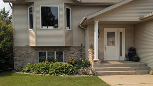 A two-story house with a front porch, a brick foundation, and a well-maintained lawn.