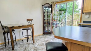 A kitchen with a marble floor, wooden furniture, a glass display cabinet, and a view through the window.