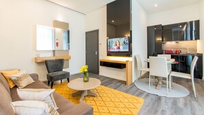 Ein modernes Wohnzimmer mit Sofa, Sessel, Couchtisch und Fernseher.