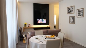 Ein modernes Wohnzimmer mit Essbereich, einem an der Wand montierten Flachbildfernseher und gerahmten Bildern.