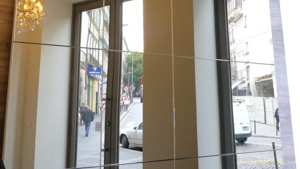 En hotellobby med en stor glasdörr, en kristallkrona och utsikt över gatan utanför.