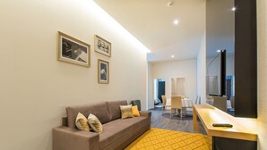 A modern living room with a sofa, a yellow rug, and framed pictures on the wall. - Letheshome Apartments 103 (Oporto)