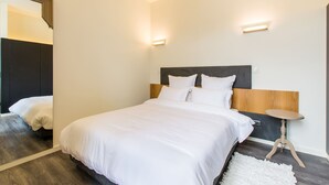 A modern hotel room with a large bed, a small round table, and a mirror. - Letheshome Apartments 205 (Oporto)