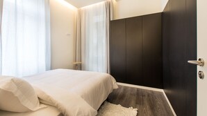 Ein Schlafzimmer mit Bett, Vorhängen, einem Kleiderschrank und einer Tür.
