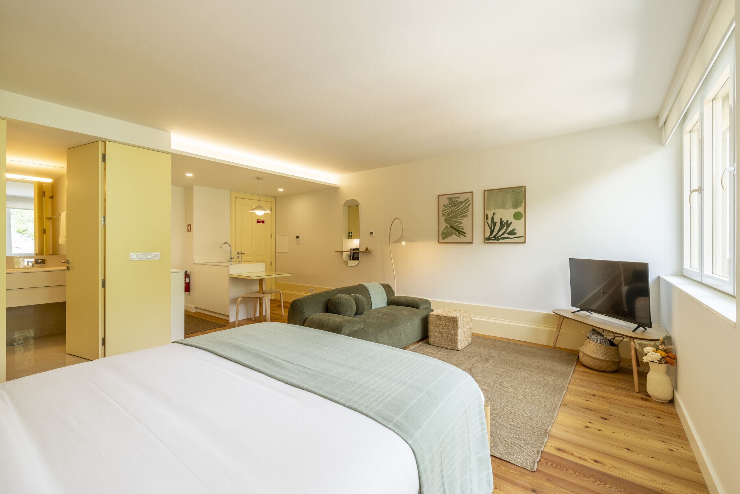 A hotel room with a bed, a sofa, a TV, a desk, and a bathroom.