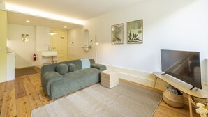 Ein Wohnzimmer mit einer Couch, einem Fernseher und einem kleinen Tisch.