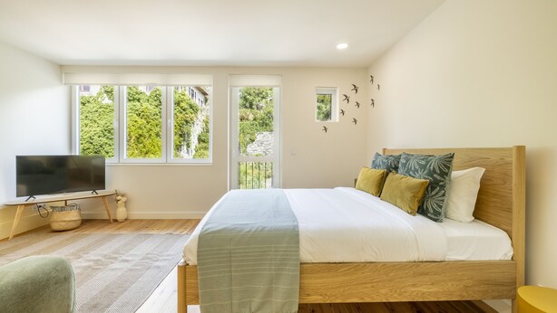 Ein Schlafzimmer mit Bett, Fernseher und Fenstern.