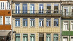 Ein mehrstöckiges Gebäude mit Balkonen, einem Eingang im Erdgeschoss und einem sichtbaren Schaufenster.