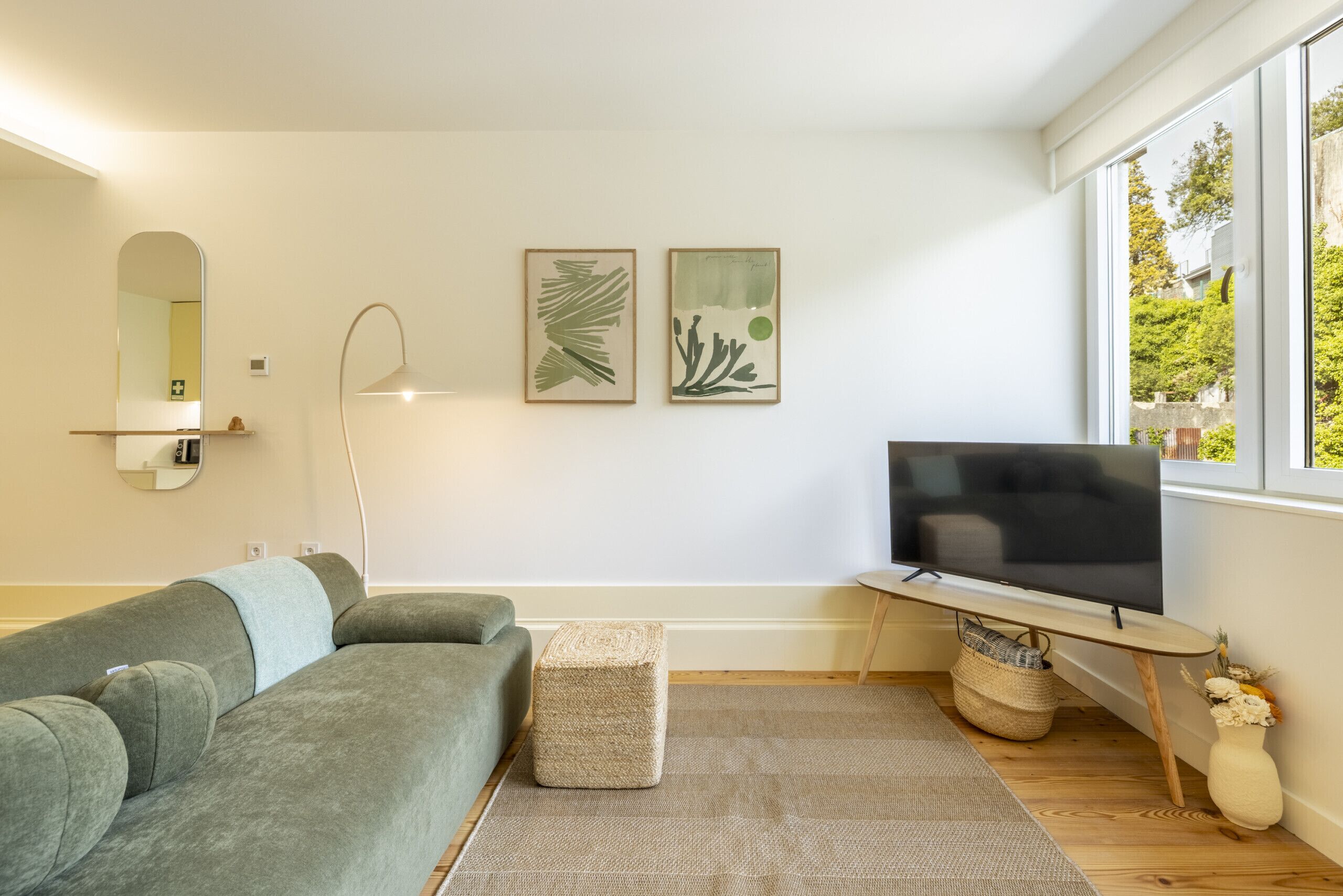 Un salón moderno con un sofá gris, un televisor de pantalla plana, una mesita y dos obras de arte enmarcadas en la pared.