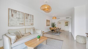 A modern living room with a sofa, coffee table, and dining area. - LXR Elviria Hills 2-Bedroom Apartment with Heated Pool (Marbella)