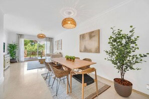 A modern dining area with a wooden table, wicker chairs, and a potted plant. - LXR Elviria Hills 2-Bedroom Apartment with Heated Pool (Marbella)