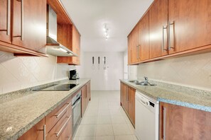 Eine Küche mit Holzschränken, Granit Arbeitsplatten, einem Herd und einem Geschirrspüler.