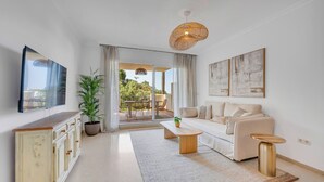 A modern living room with a sofa, coffee table, and a dining area with a table and chairs. - LXR Elviria Hills 2-Bedroom Apartment with Heated Pool (Marbella)