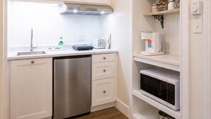 A compact kitchen with white cabinetry, a stainless steel dishwasher, a microwave, and a built-in oven. - Modern Guest Suite with Gym & Sauna (Pubnico)